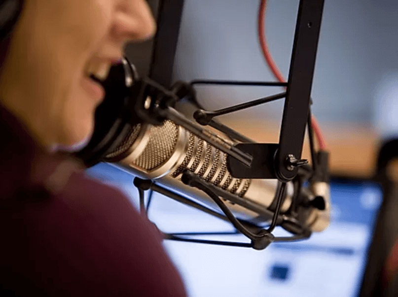 Radio host speaking into studio mic with pop filter